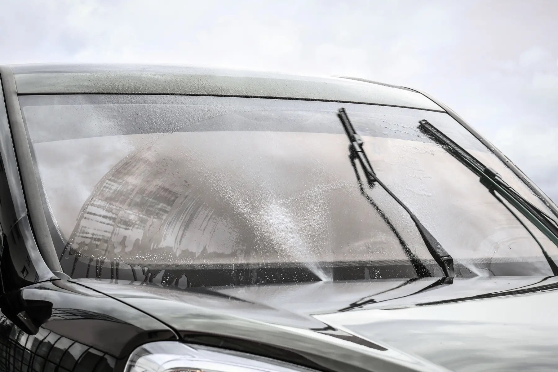 Nasse Autowindschutzscheibe mit Scheibenwischern vor der Reinigung mit dem SHILOX Glasreiniger