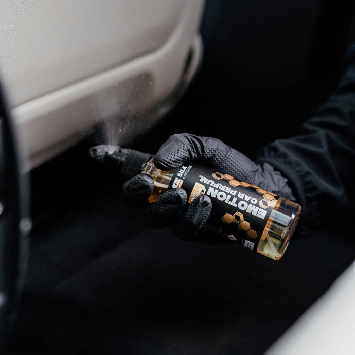 Autoparfum wird im Fahrzeuginnenraum auf Türverkleidung gesprüht